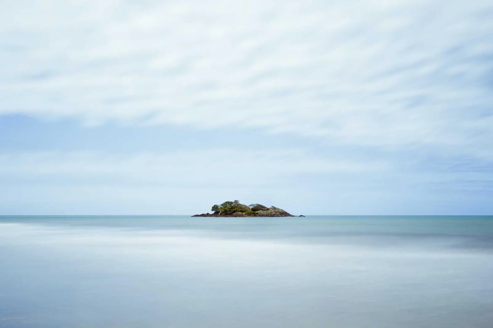 Mar calmo e prateado com uma pequena ilha no horizonte